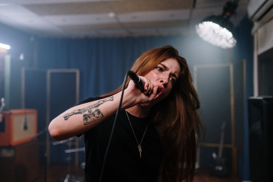 Dynamic moment of a tattooed female singer passionately performing in a music studio.