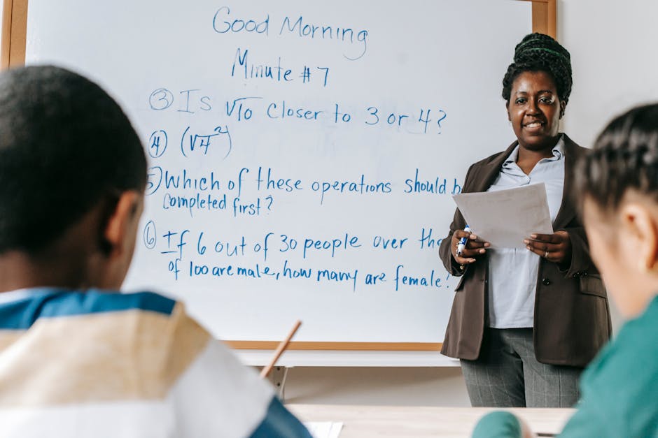 Cheerful African American female math teacher standing near whiteboard and explaining new material to multiracial pupils